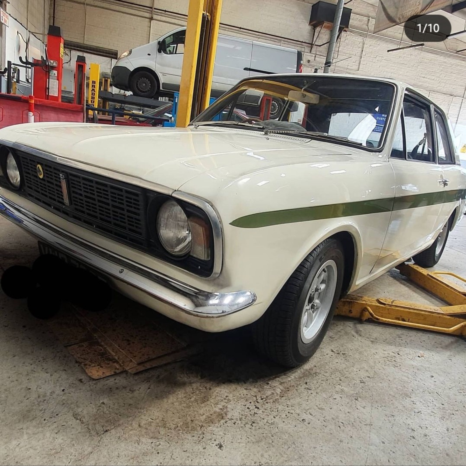 A car raised on the ramp inside the Southall MOT Services workshop bay